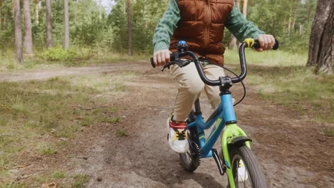 Child cycling forward on empty forest path front view Stock Footage 315756775