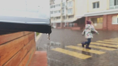 Child Dancing in the Rain with Water Dripping off of the Roof Drain Stock Footage 123723600