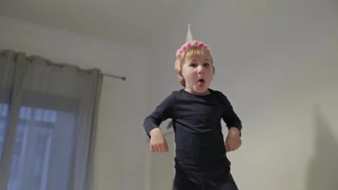 Child dancing wearing party hat in bedroom Stock Footage 308682699