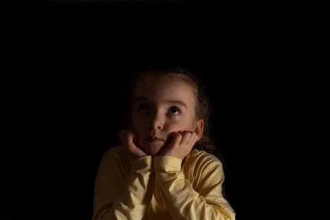 A child on a dark background thinks and dreams Stock Photos