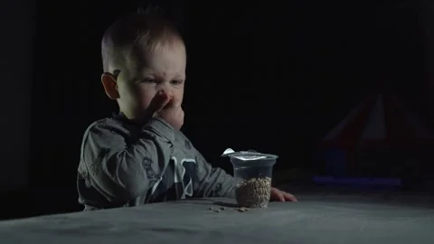 A child in the dark eats seeds before going to bed, licks his fingers Stock Footage 147493968
