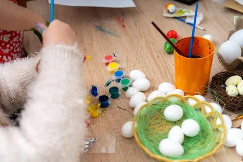 Child decorates styrofoam Easter eggs at table during holiday celebration Stock Photos