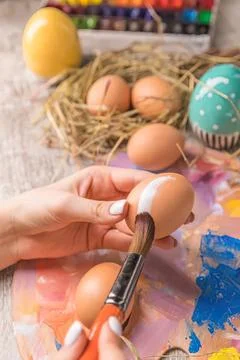 Child decorating easter eggs with paint and brush at table Stock Photos
