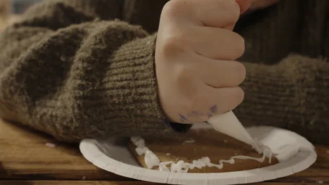 Child decorating a gingerbread cookie with icing Stock Footage 346193112
