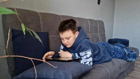 Child deeply engrossed in tablet gaming exploring digital realms Immersed in Stock Footage 265962259