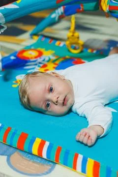 Child development. The baby lies on the developing mat and plays with toys... Stock Photos