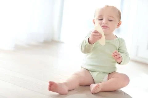 Child development, eating and teething biscuit with toddler on floor in liv.. Stock Photos
