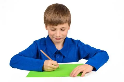 Child development: a schoolboy boy in a blue T-shirt sits at the table and dr Foto stock