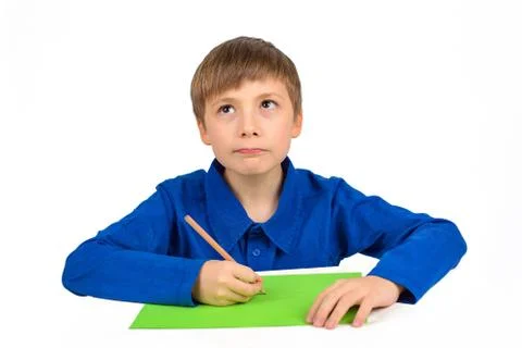Child development: a schoolboy boy in a blue T-shirt sits at the table and dr Stock Photos