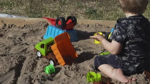 Child develops motor skills while playing in sandbox Stock Footage 314308596