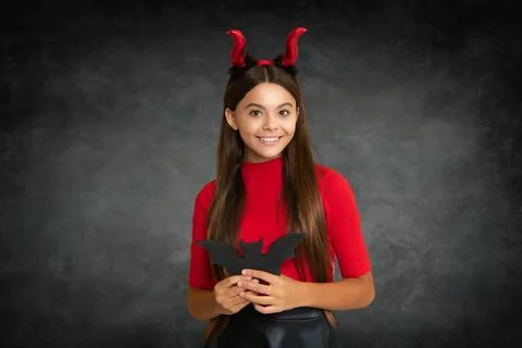Child with devil horns hold bat symbol of Halloween Halloween witch girl. Little Stock Photos
