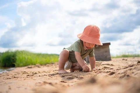 Child digging in sand with orange hat Stock-Fotos
