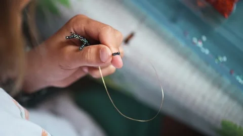 A child is diligently crafting delicate beadwork, weaving intricate ornaments Stock Footage 249258401