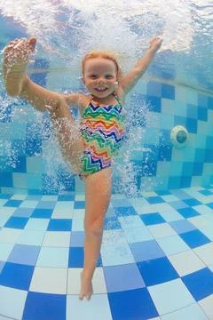 Child dive in pool, jump deep down underwater from poolside Stock Photos