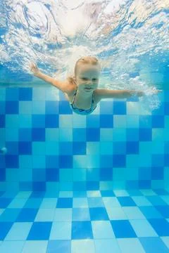 Child dive in pool, jump deep down underwater from poolside Stock Photos