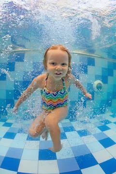 Child dive in pool, jump deep down underwater from poolside Stock Photos