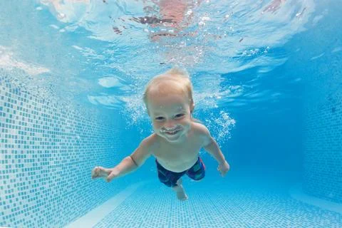 Child dive in pool, jump deep down underwater from poolside Stock Photos