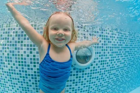 Child dive in pool, jump deep down underwater from poolside Stock Photos
