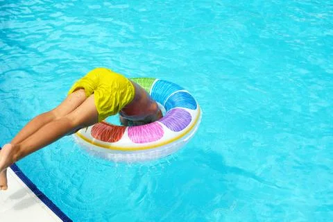 Child dives into pool with float; summer fun unleashed. Captures the joy of 스톡 사진