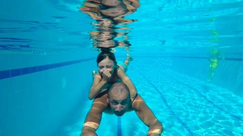Child diving on father back in pool. Video stock 233120676