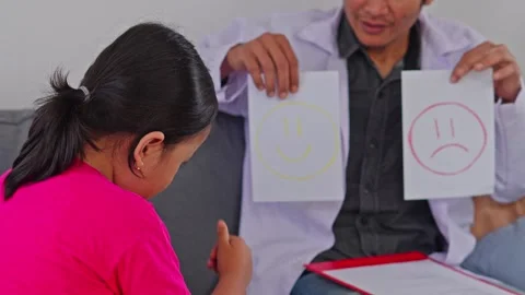 Child doctor using emotional smiley cards to evaluate little girl patient's mood Vídeo Stock 340259396
