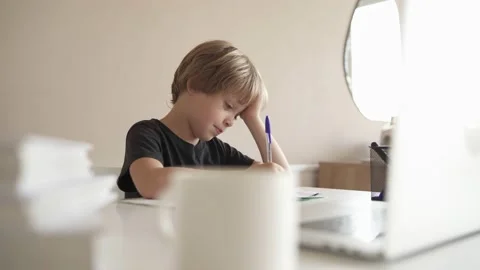 A child does homework using a laptop while sitting at home in the kitchen at the Stock Footage 142032128