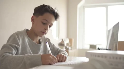 A child does homework using a laptop while sitting at home in the kitchen at the Video stock 142033010