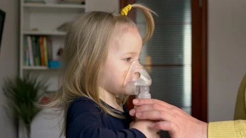 The child does the inhalation procedure with a nebulizer of the respiratory trac Stock Footage 147979419