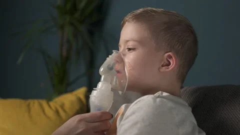 The child does the lung inhalation procedure at home. Inhalation when coughing.  Stock Footage 165826391