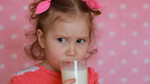 The child does not want to drink milk, takes a sip and frowns. Cute little girl Stock Footage 88649479