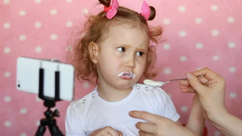 The child does not want to eating yogurt. The mother tries to feed the baby with Stock Footage 88649054