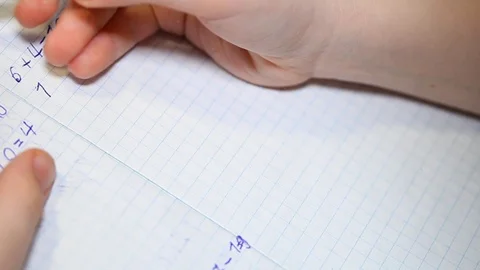 The child does school homework, solves arithmetic examples and writes them in a Stock Footage 125874818