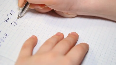 The child does school homework, solves arithmetic examples and writes them in a Stock Footage 126096307