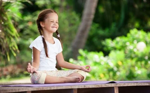 Child doing exercise on platform outdoors. Healthy lifestyle. Yoga girl Foto stock