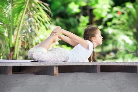 Child doing exercise on platform outdoors. Healthy lifestyle. Yoga girl Foto stock