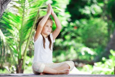 Child doing exercise on platform outdoors. Healthy lifestyle. Yoga girl Stock-Fotos