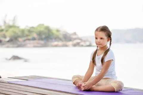 Child doing exercise on platform outdoors. Healthy lifestyle. Yoga girl Foto stock