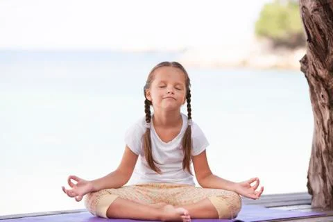 Child doing exercise on platform outdoors. Healthy lifestyle. Yoga girl Foto stock