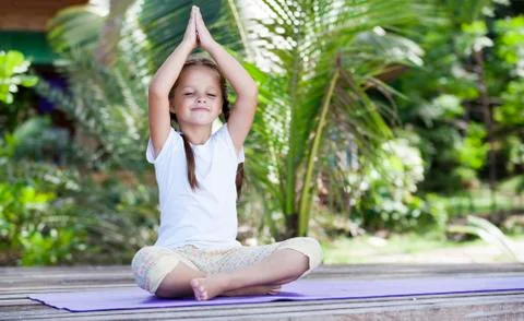 Child doing exercise on platform outdoors. Healthy lifestyle. Yoga girl Foto stock