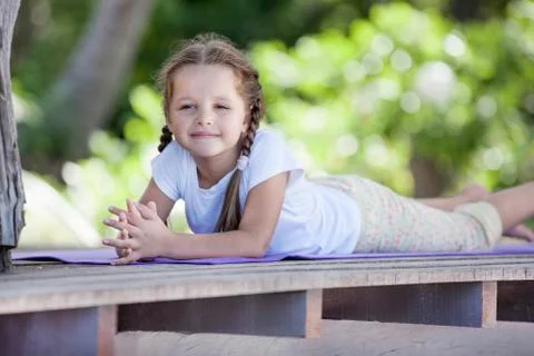 Child doing exercise on platform outdoors. Healthy lifestyle. Yoga girl Stock Photos