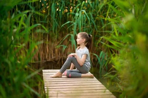 Child doing exercise on platform outdoors. Healthy lifestyle. Yoga girl Stock Photos