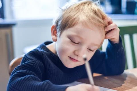 Child doing homework at the kitchen table at home during lockdown Stock Photos
