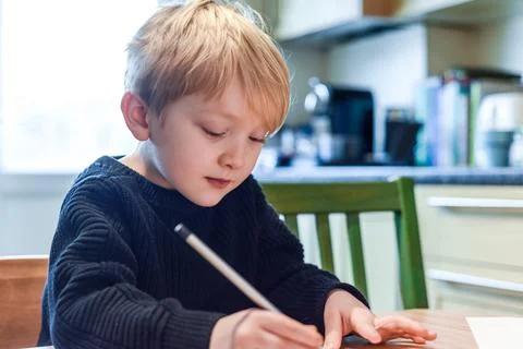 Child doing homework at the kitchen table at home during lockdown Stock Photos