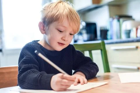 Child doing homework at the kitchen table at home during lockdown Stock Photos