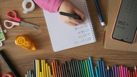 Child doing math test in notebook using smartphone calculator to solve equation Stock Footage 284931401