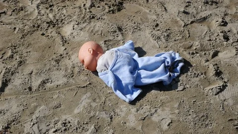 Child doll left alone on sandy playground Stock Footage 88597898