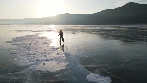 A child in a down jacket is clumsily skating on the winter Lake Baikal Video stock 278020608