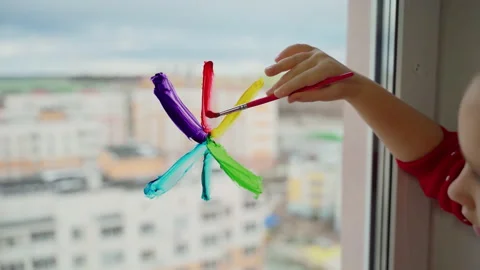 Child draw snowflake in rainbow colours on window with paints Stock Footage 166152247
