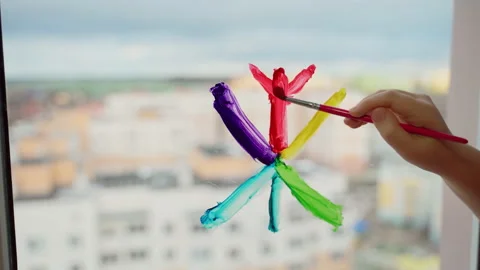 Child draw snowflake in rainbow colours on window with paints Stock Footage 166152389
