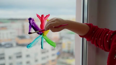Child draw snowflake in rainbow colours on window with paints Stock Footage 166153735